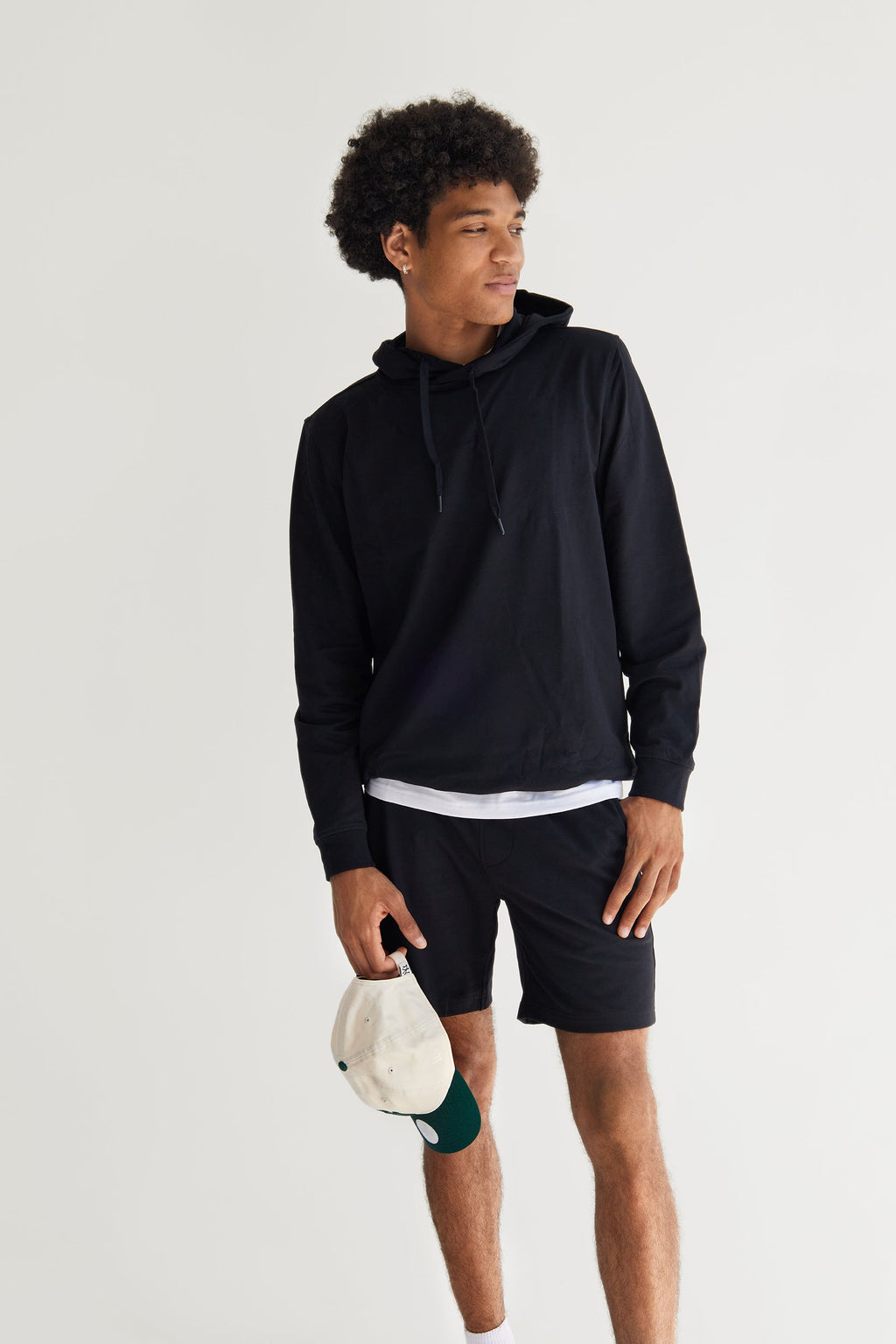 Person wearing a black hoodie and shorts holding a paddle on a white background