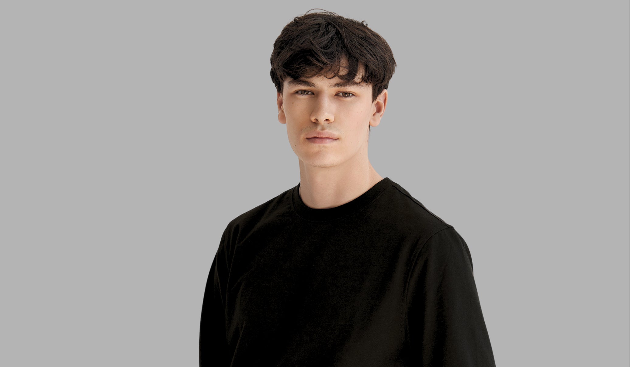 Person wearing a black shirt against a gray background