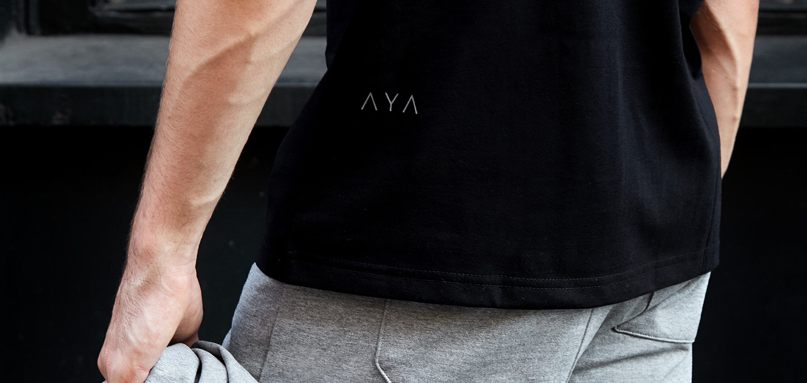 Person wearing a black t-shirt with 'AVA' logo, standing outdoors.