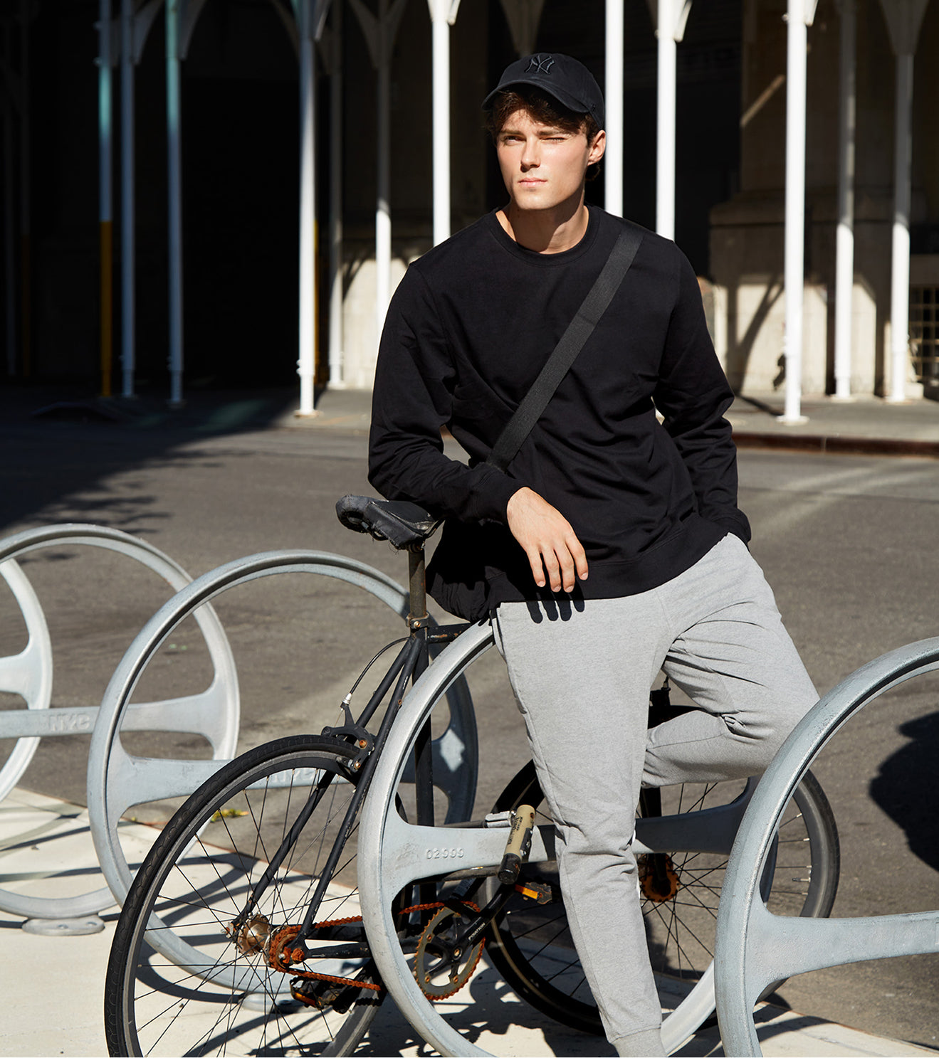 Person in black shirt and gray pants sitting on a bicycle in an outdoor setting